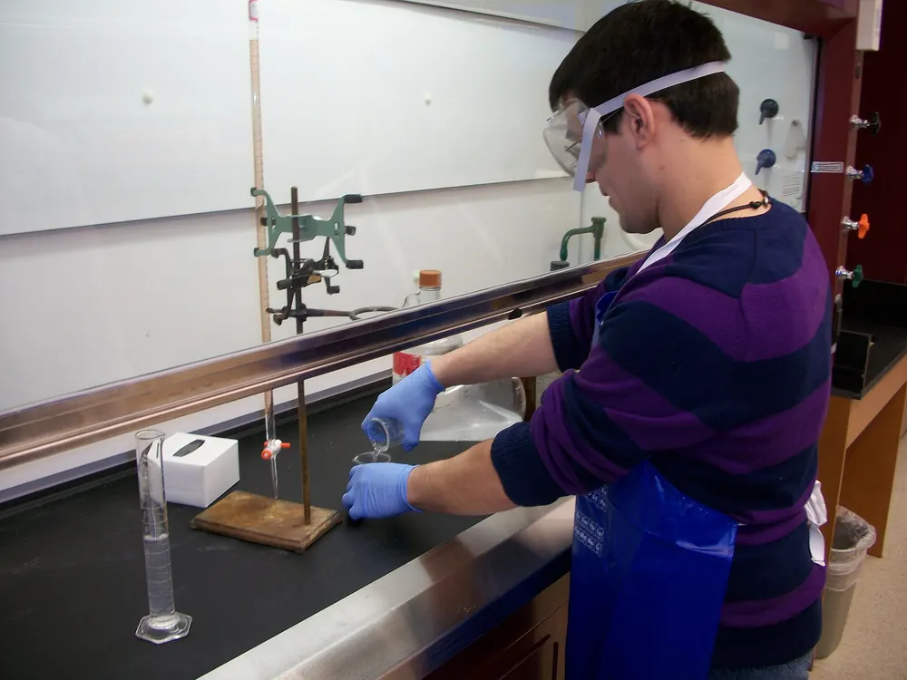 Student in safety goggles working inside a laboratory fume hood