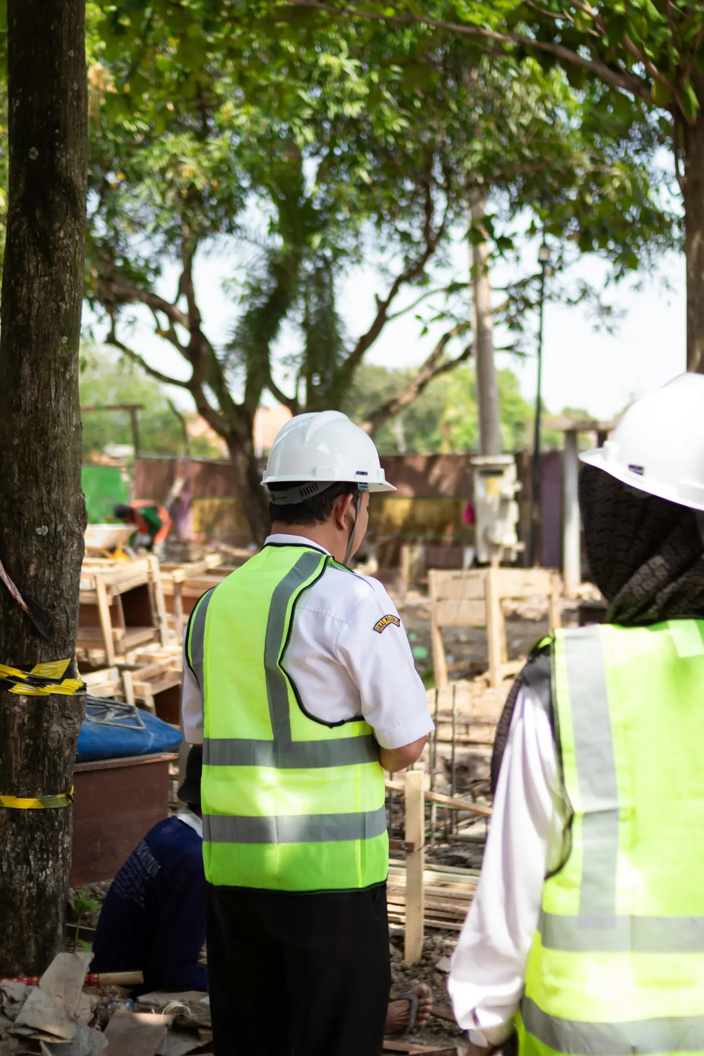 Two workers in hard hats and safety vests reviewing a site together