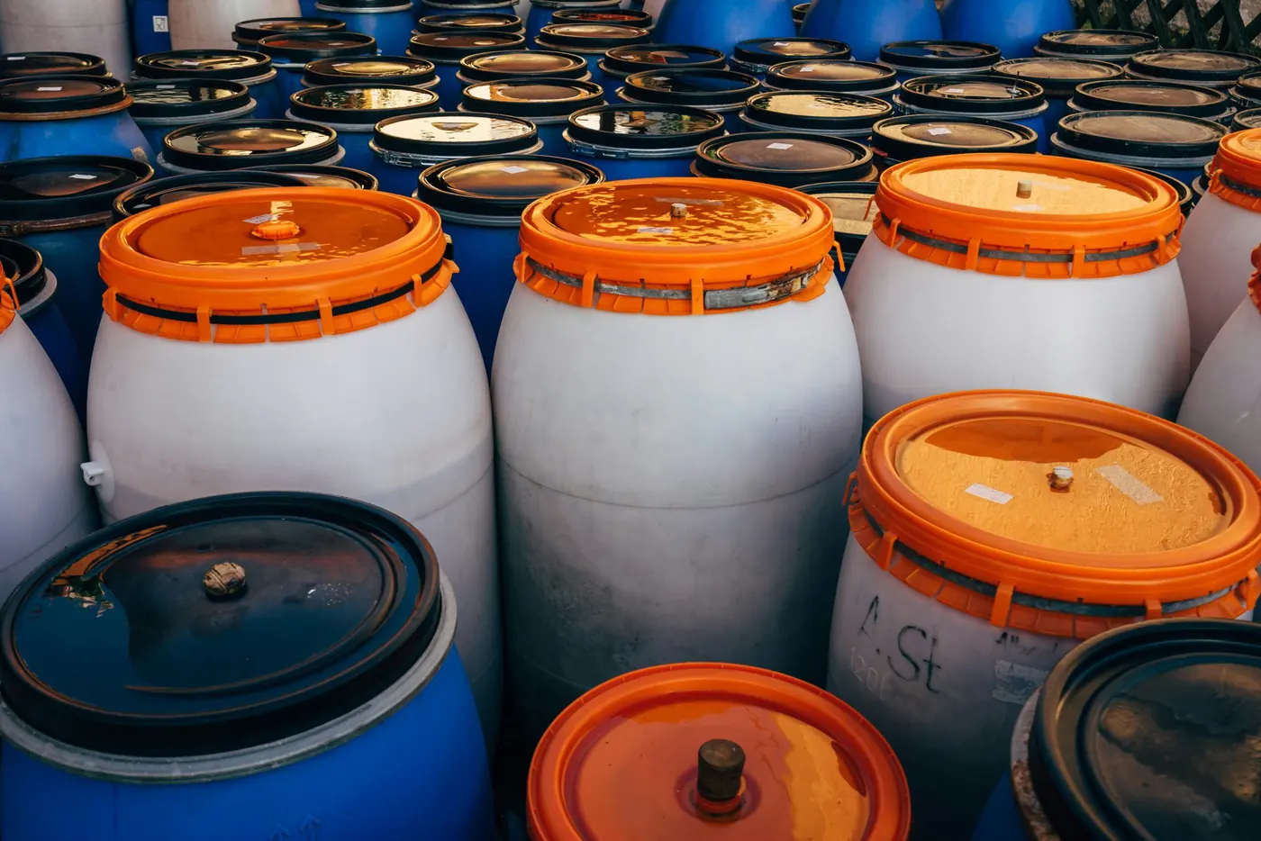 Rows of chemical drums with orange and blue lids