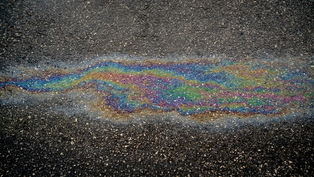 Rainbow sheen of a fuel spill on wet pavement